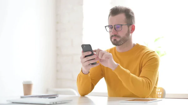 Attractive Middle Aged Man using Smartphone in Office