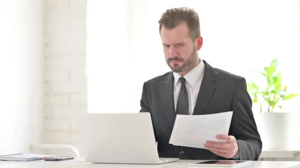 Empresario Con Computadora Portátil Que Tiene Pérdida Mientras Lee Documentos — Foto de Stock