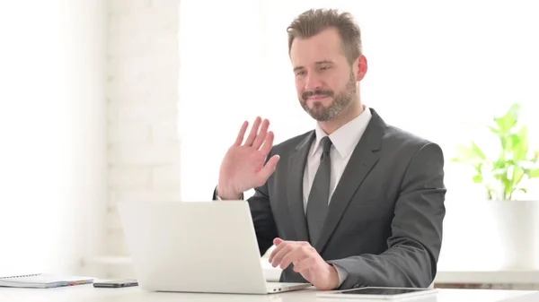 ビジネスマンがオフィスのノートパソコンでビデオ通話で話す — ストック写真