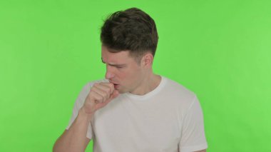 Sıradan bir genç adam öksürüyor Yeşil arka planda kendini kötü hissediyor