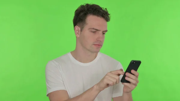 Случайный Молодой Человек Просматривает Смартфон Зеленом Фоне — стоковое фото
