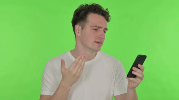 カジュアル若い男損失上のスマートフォン緑の背景 — ストック写真