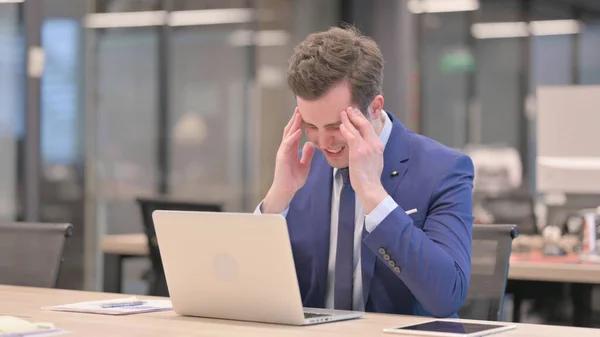 ラップトップで働いている間に頭痛を持っている中年のビジネスマン — ストック写真