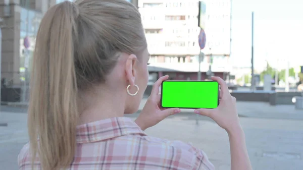 Casual Woman Holding Horizontal Smartphone with Green Screen Outdoor