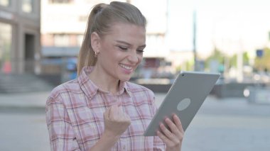 Casual Woman Celebrating Success on Tablet Outdoor
