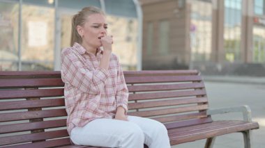 Casual Woman Coughing while Sitting on Bench Outdoor