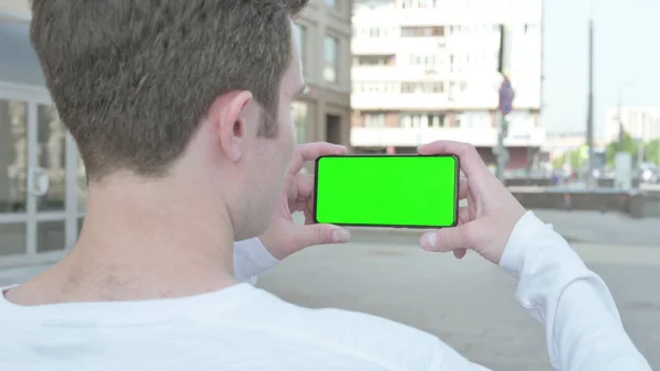 Casual Man Holding Horizontal Smartphone with Green Screen Outdoor