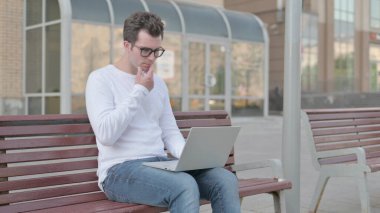 Thinking Casual Man Using Laptop while Sitting Outdoor on Bench