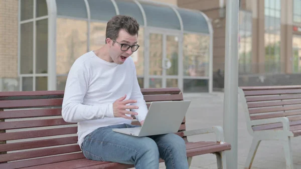 Casual Man Celebrating Success on Laptop while Sitting Outdoor on Bench
