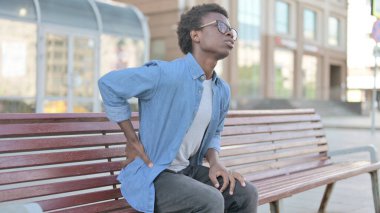 Afrikalı Adam Bench Outdoor 'da otururken sırt ağrısı çekiyor
