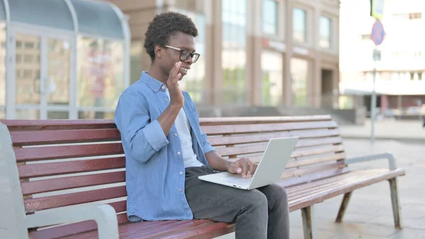 African Man Talking on Video Call while Sitting Outdoor on Bench