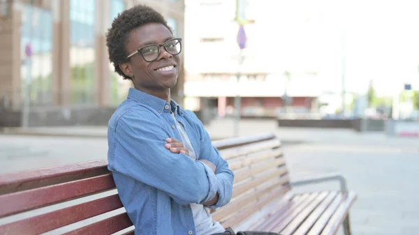 African Man Smiling Camera While Sitting Bench Stockfoto