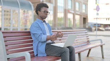 Bilek ağrısı olan adam Bench 'te otururken dizüstü bilgisayar kullanıyor.
