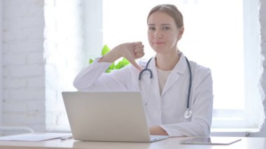 Klinikte otururken Başparmağını gösteren kadın doktor.