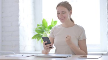 Successful Young Woman Celebrating Win on Smartphone