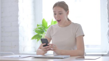 Successful Young Woman Celebrating Win on Smartphone
