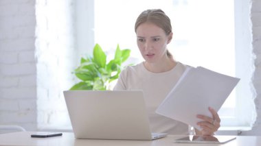 Young Woman Upset while Reading Business Report at Work