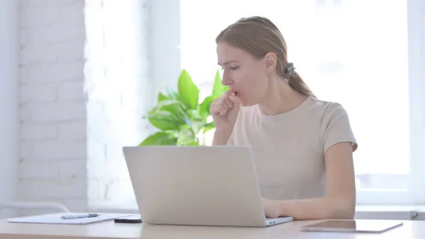 Young Woman Coughing while Working on Laptop