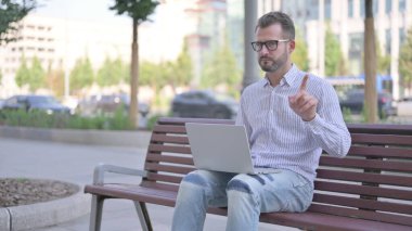 Rejecting Adult Man in Denial While using Laptop Sitting Outdoor on Bench