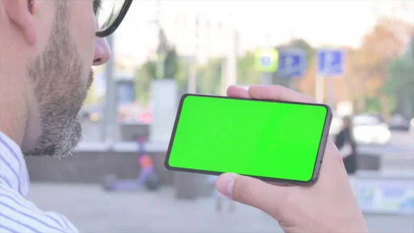 Close Up of Adult Man Holding Horizontal Smartphone with Green Screen Outdoor