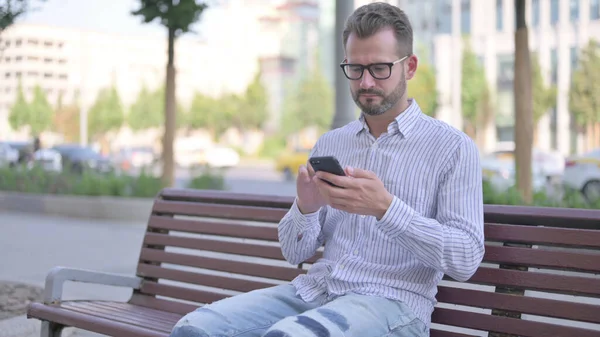 Adult Man Using Smartphone While Sitting Outdoor Bench — Foto de Stock