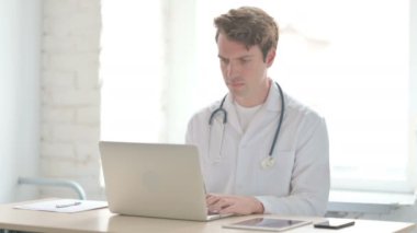 Klinikte dizüstü bilgisayarda çalışan erkek doktor.
