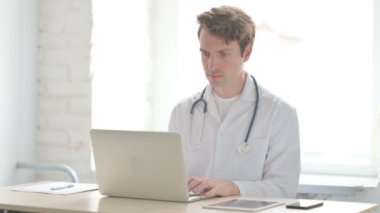 Male Doctor Smiling at Camera While sitting in Clinic
