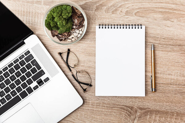 Пустой блокнот с ручкой лежит на деревянном столе на рабочем месте, вид сверху