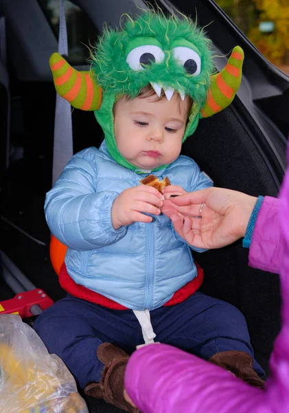 衣装を着た赤ん坊がハロウィーンのバンの後ろで軽食を食べています — ストック写真