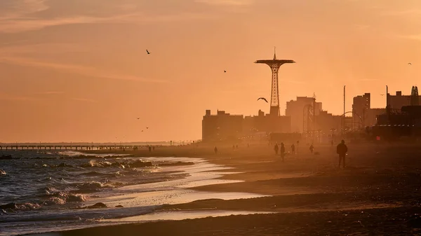 Scenes at Coney Island beach as the last rays of the evening sun fall onto the water