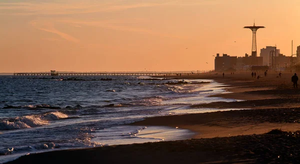 Scenes at Coney Island beach as the last rays of the evening sun fall onto the water