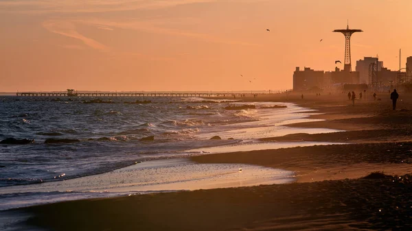 Scenes at Coney Island beach as the last rays of the evening sun fall onto the water