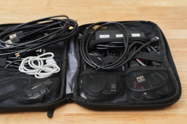 Bir seyahat çantasında çalışma masasında bulunan elektrik ve şarj kabloları.