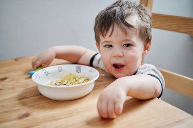 Küçük çocuk kahvaltıda yumurta yiyor ve surat asıyor.