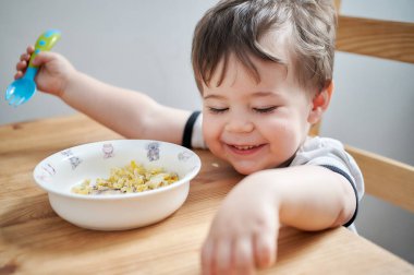 Küçük çocuk kahvaltıda yumurta yiyor ve surat asıyor.