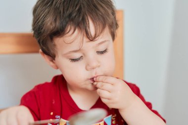 Bir çocuk kahvaltı için mutfak masasında yulaf ezmesi yiyor.