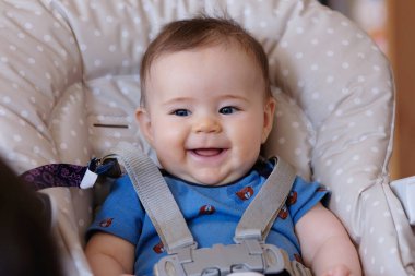 Yüksek sandalyedeki mutlu erkek bebek