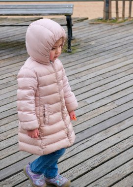 Genç ve enerjik bir kız kışın sahil yolunda koşuşturuyor.