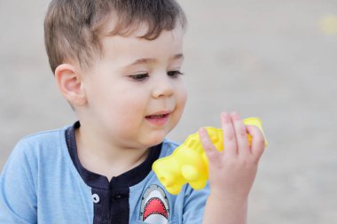 Tatlı çocuk kumdaki kumsal oyuncaklarıyla oynuyor. Portre.