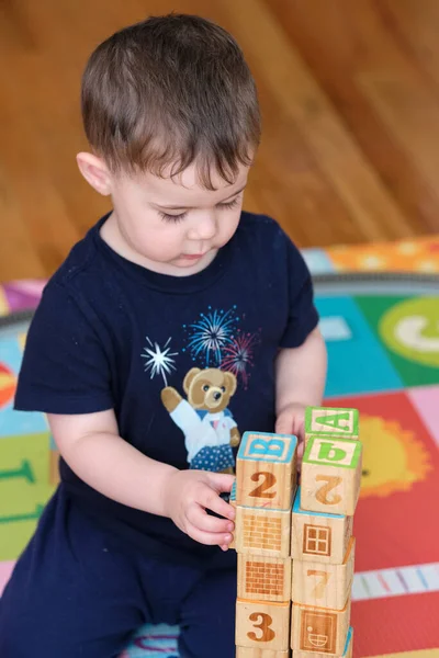 蹒跚学步的幼儿用带有字母表的木制立方体建造结构 — 图库照片