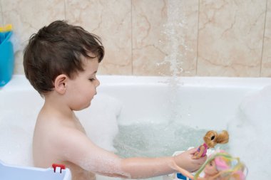 Genç çocuk bebeklerle oynarken banyo yapıyor.