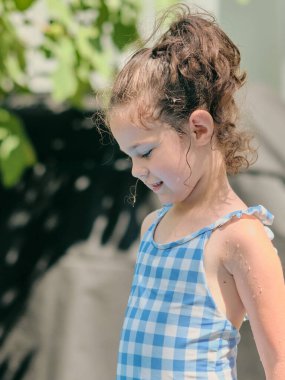 Erkek ve kız kardeş arka bahçede bir su havzasının yanında oynuyorlar.