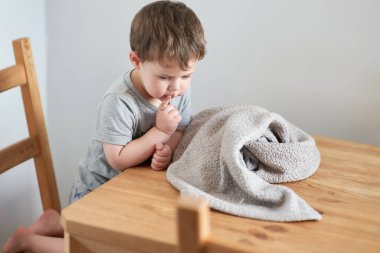 Şirin çocuk mutfak masasında soytarılık yapıyor.