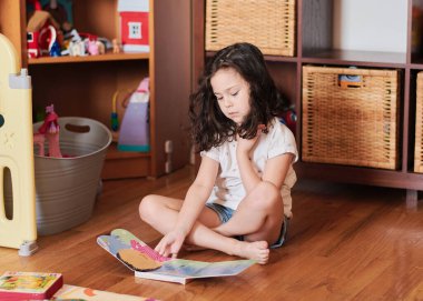 Genç kız yerde kitap okuyor.