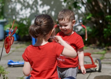 Kardeşler güneşli bir günde arka bahçede sabun köpüğüyle oynuyorlar.