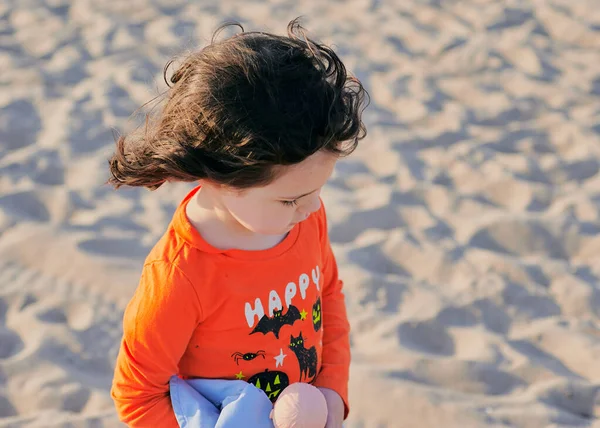 若い女の子はハロウィーンのシャツで暖かい日にビーチで遊んでいます — ストック写真