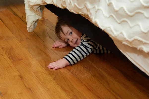 可爱的小孩躲在床底下 — 图库照片