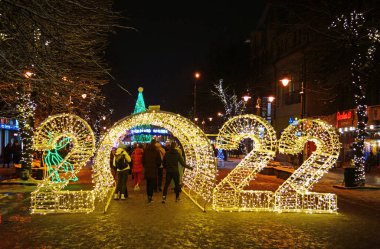 Khmelnytskyi, Ukrayna - 7 Aralık 2021: 2022 noel sokak dekorasyonunda insanlar ışık kemerlerinde yürüyorlar. Khmelnytskyi Noel sokak dekorasyonları.