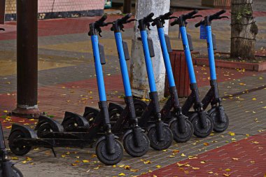 Şehre park etmiş bir sürü elektrikli scooter. Güz sokağında bir grup bisiklet..