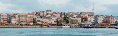 İstanbul 'daki binaların yakınındaki iskelede farklı gemi ve tekneler, pankart 